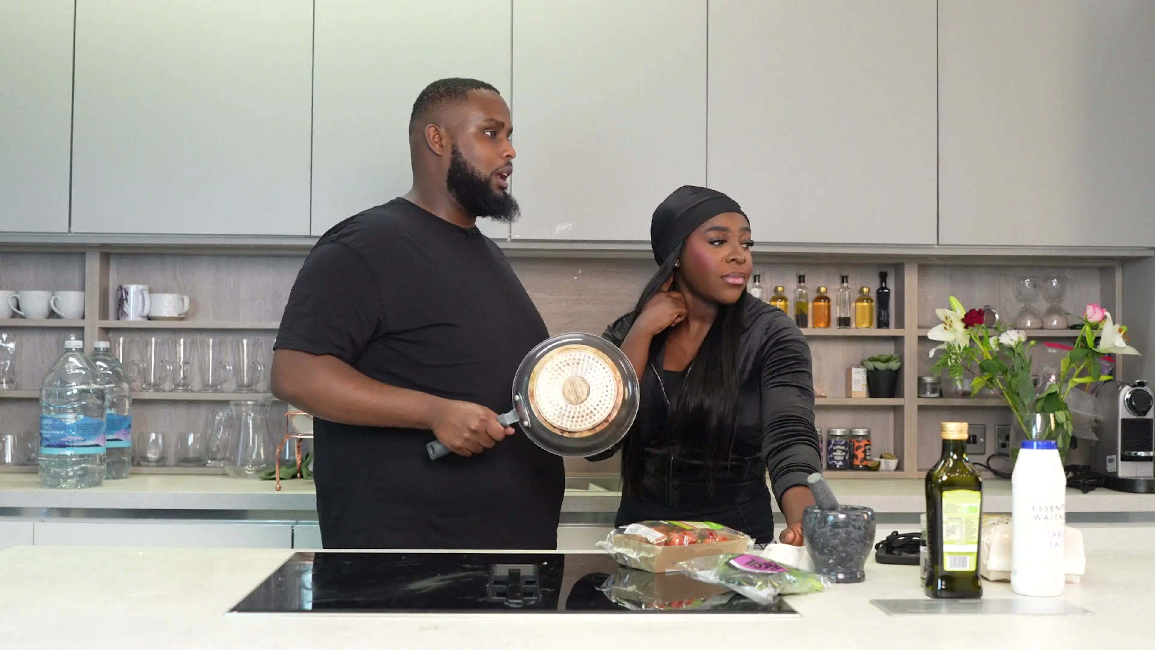 A host and a guest talking in the kitchen on the set of Behind The Stove