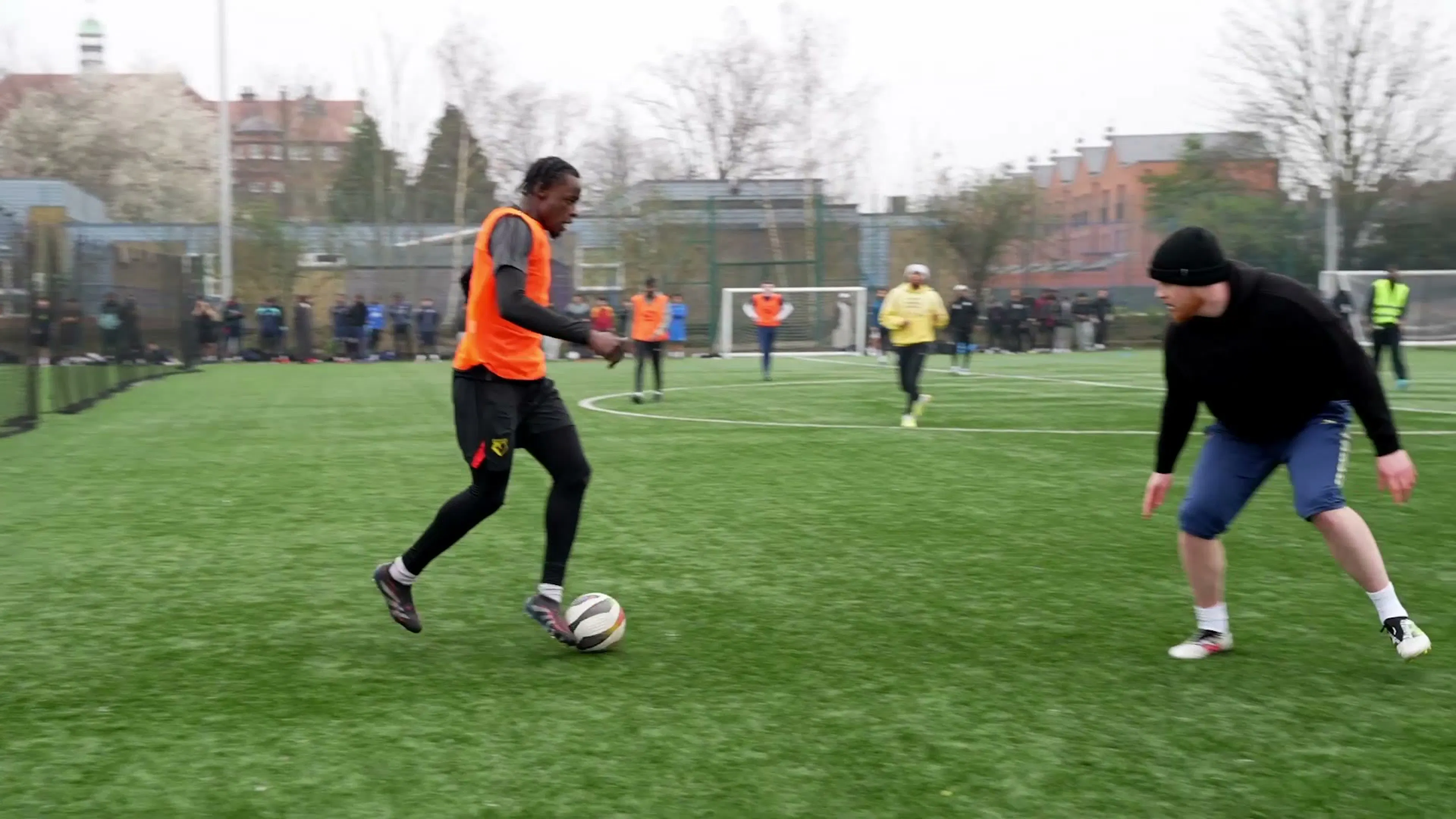 A player in an orange bib dribbling past a defender at an Onside tournament