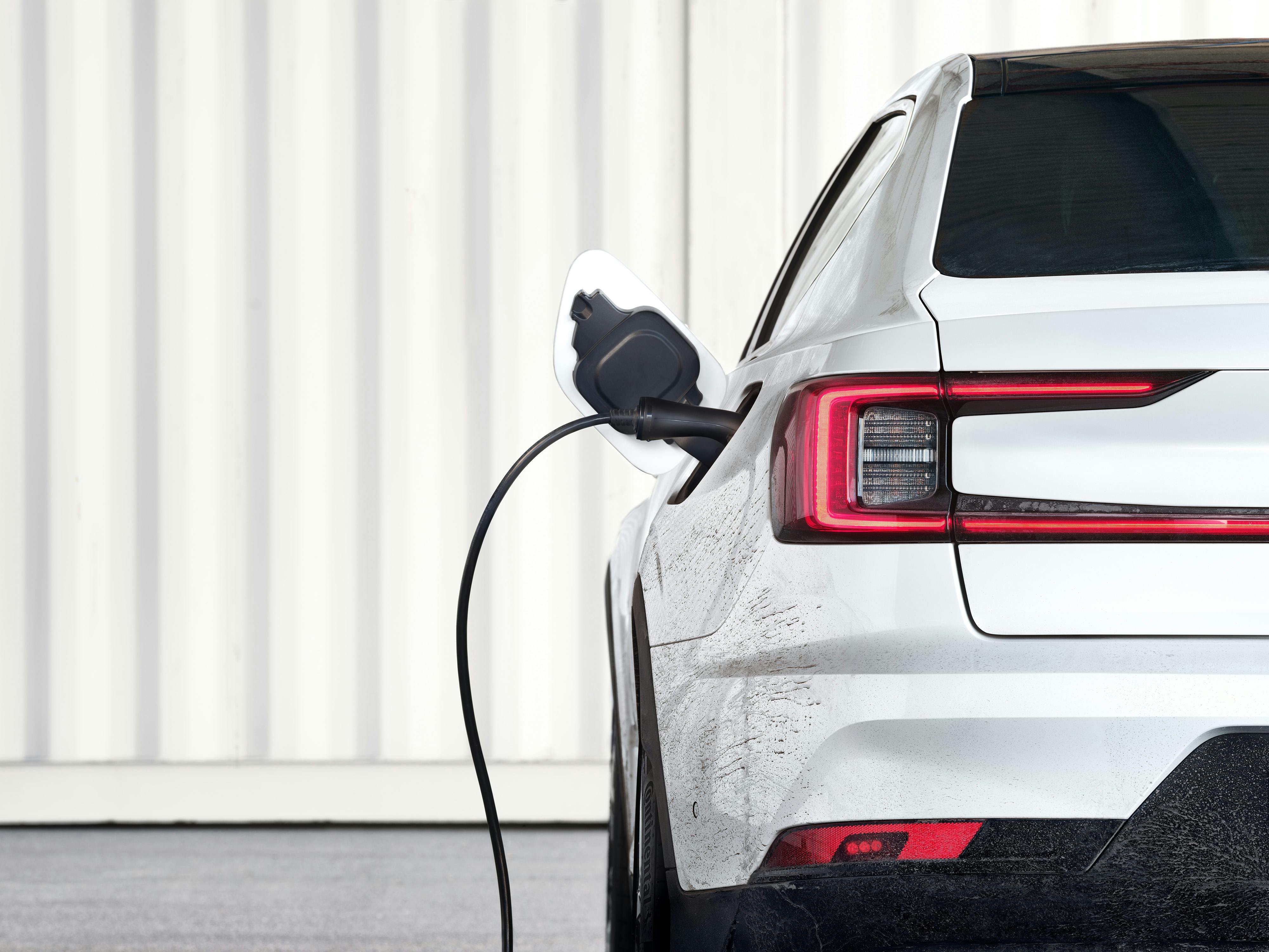 Rear view of the Polestar 2 with charging port connected to a charging station.