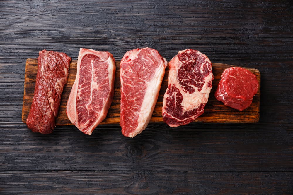 Red meat on wooden block — beef, lamb, pork
