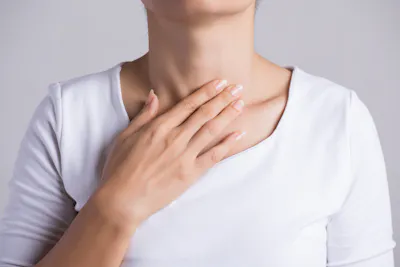 Woman touching thyroid gland on front of neck