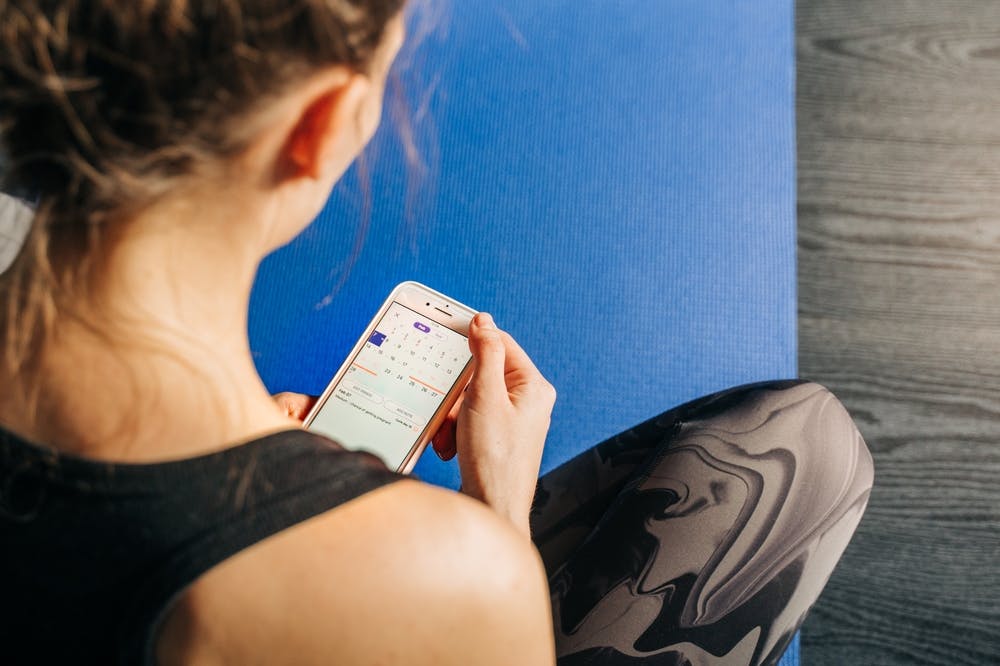 Woman looking at iPhone calendar to track menstrual cycle