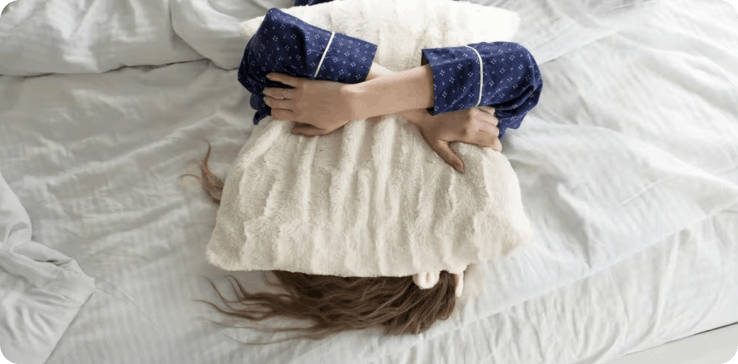 Woman in bed with pillow on face