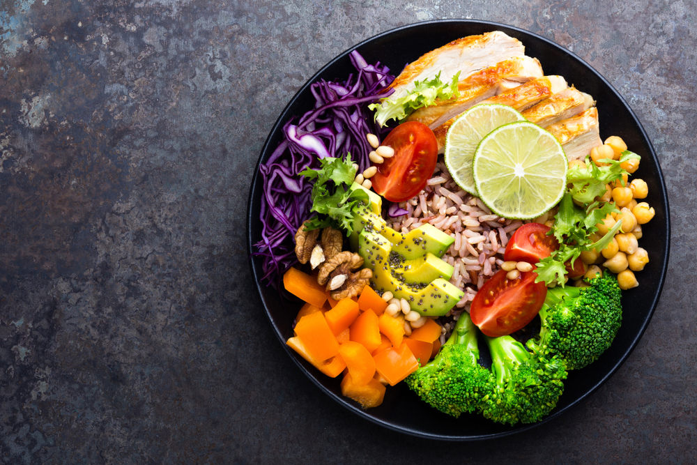 Black bowl filled with nutritious vegetables, fruits, chicken and more