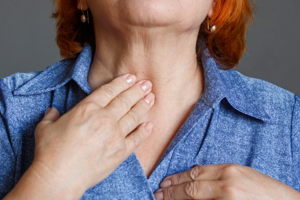 Woman touching front of neck Graves' disease