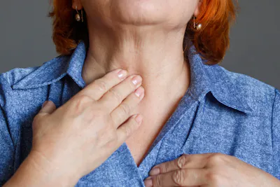 Woman touching front of neck Graves' disease