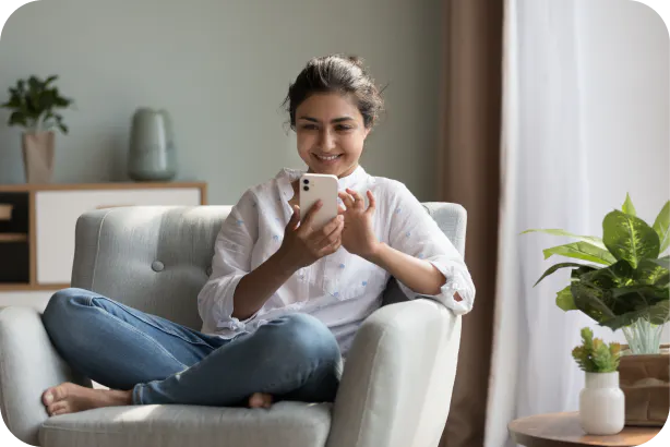 Woman sat on sofa looking at iPhone