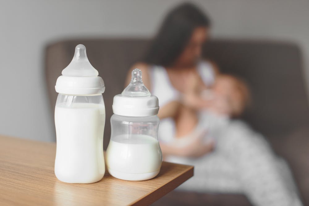 Woman breastfeeding baby with milk bottle