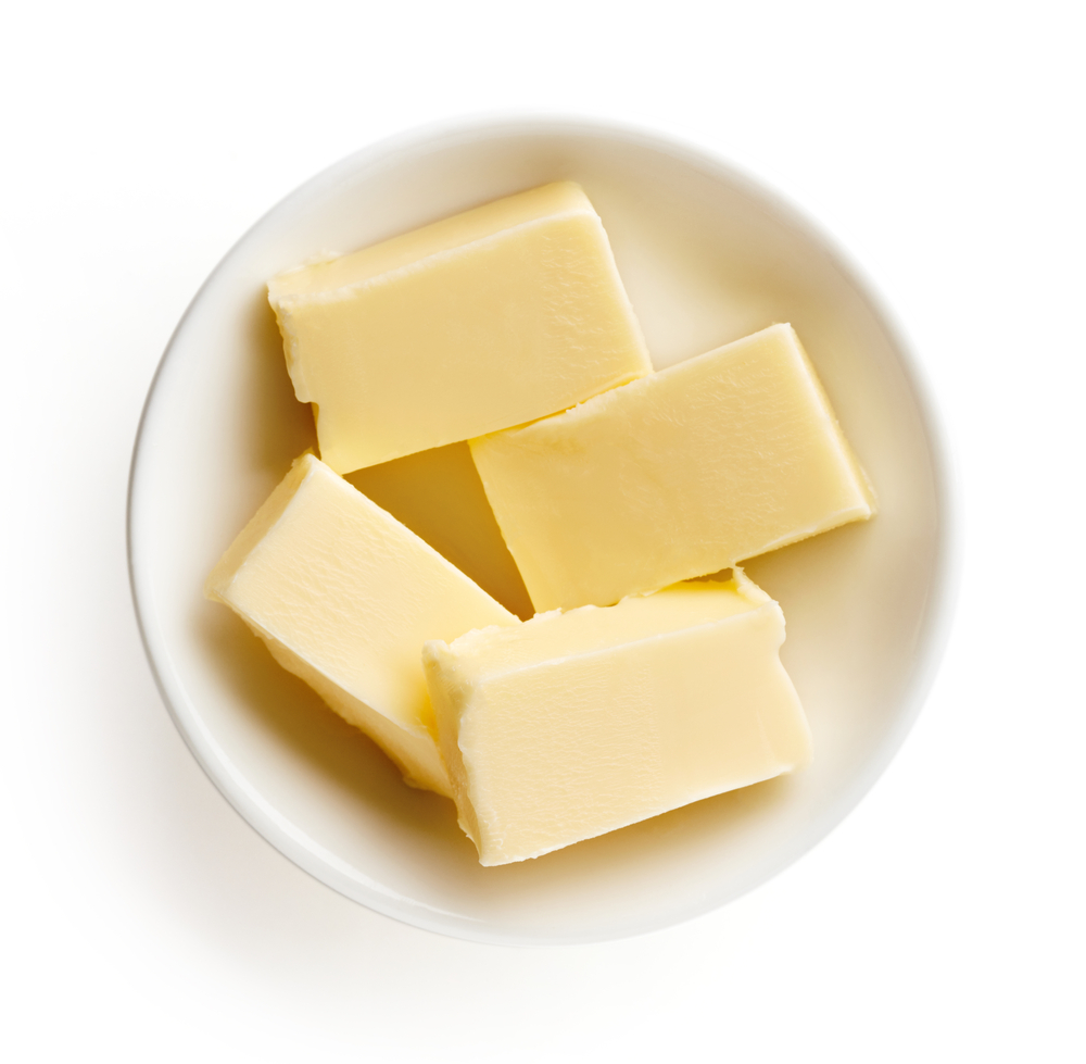 Butter pieces in bowl on white background