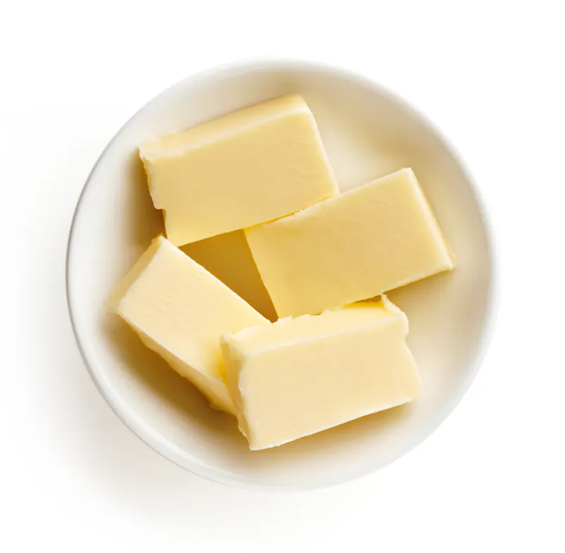 Butter pieces in bowl on white background