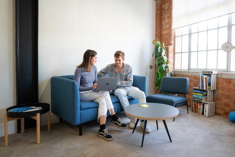 Two Thriva employees sitting on a sofa in the office