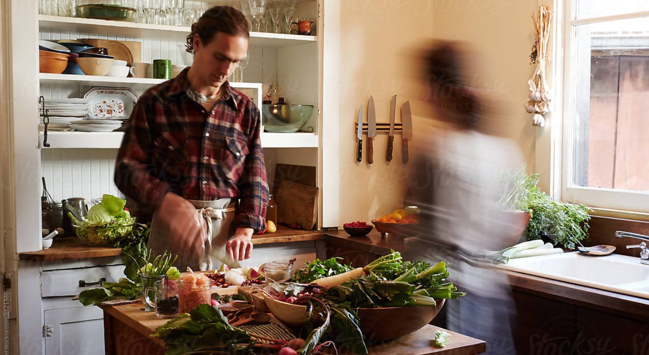A man chopping vegetables in a kitchen with Mediterranean diet components.
