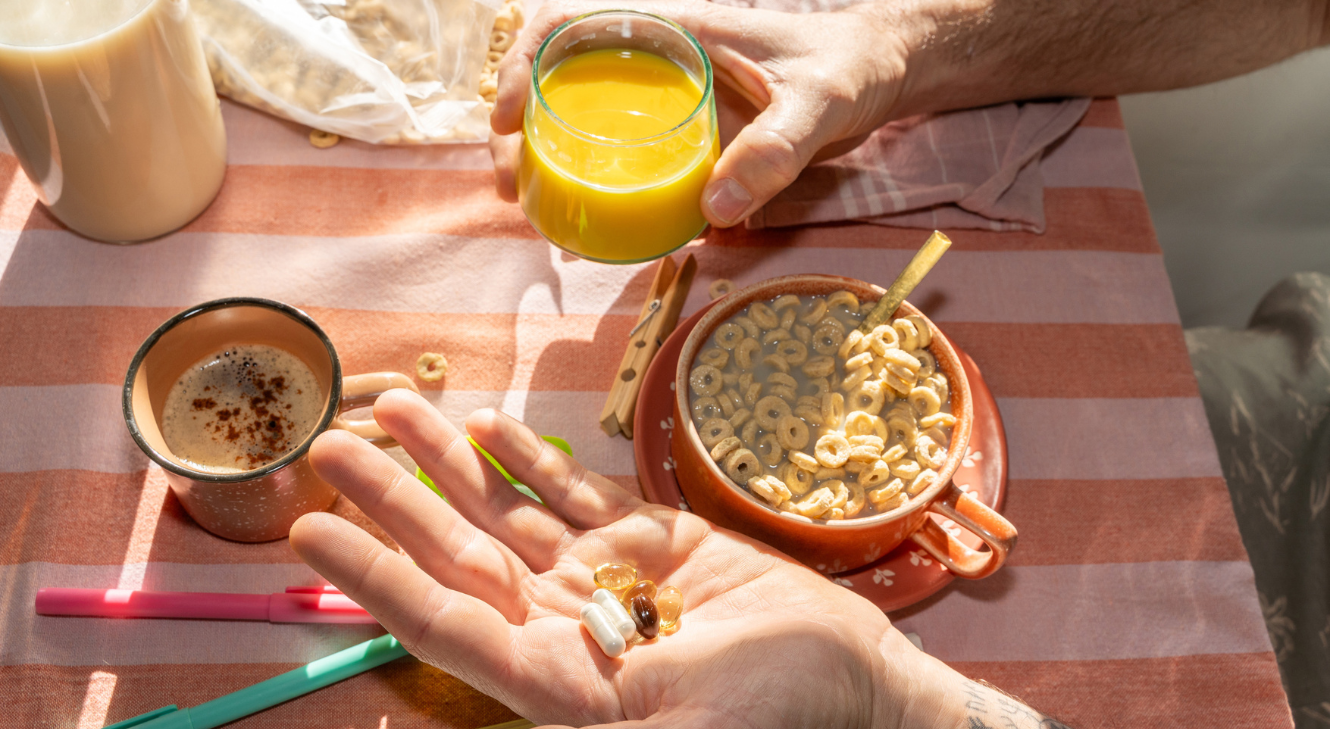 A person holding multivitamins while having breakfast.