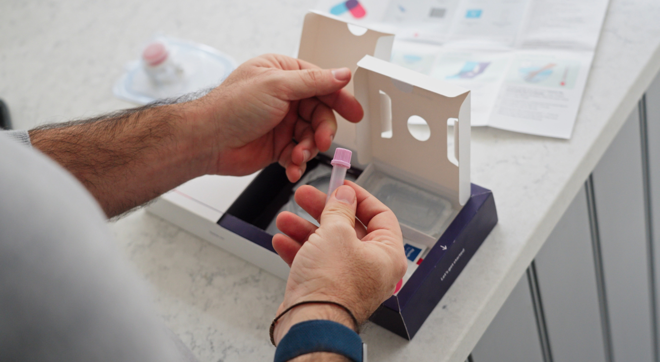 A person holding a tube with an open Thriva blood test kit.