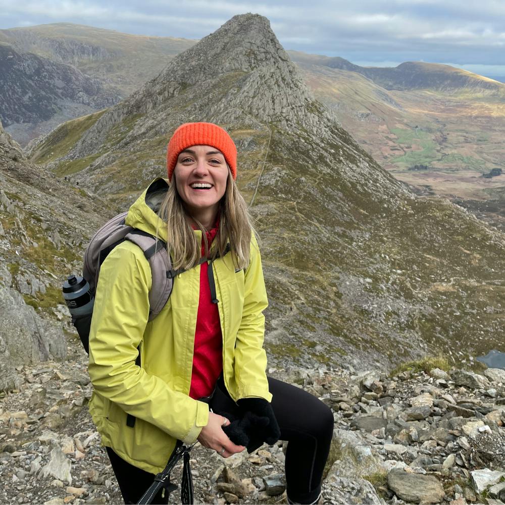 A woman standing in front of a mountain.