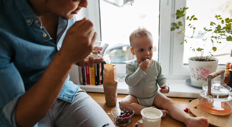 A woman and baby eating yoghurt.