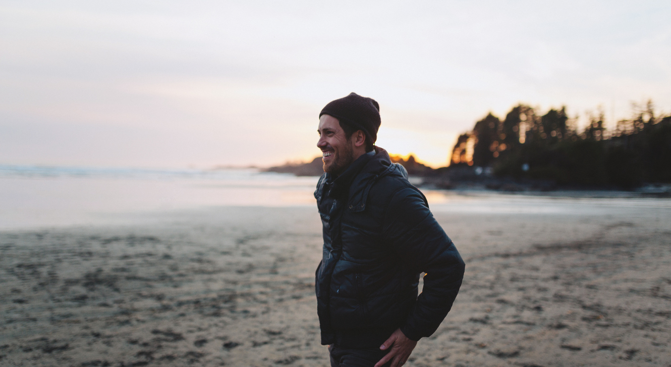 A man smiling and walking along a beach