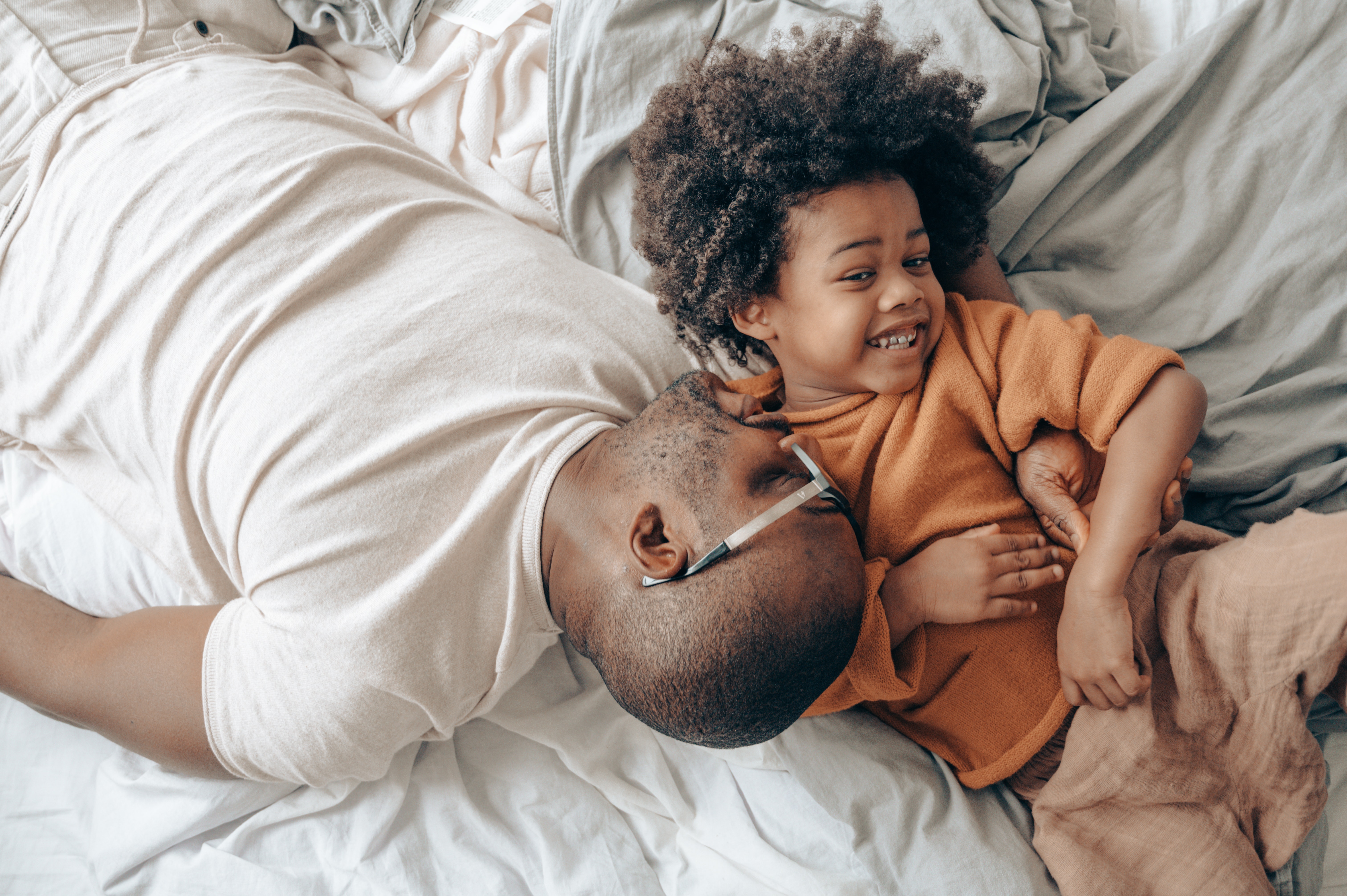 Father and son lying down on bed laughing together
