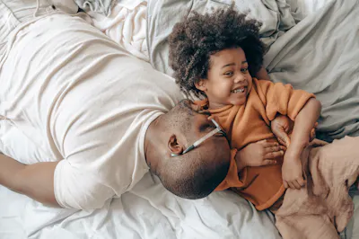 Father and son lying down on bed laughing together