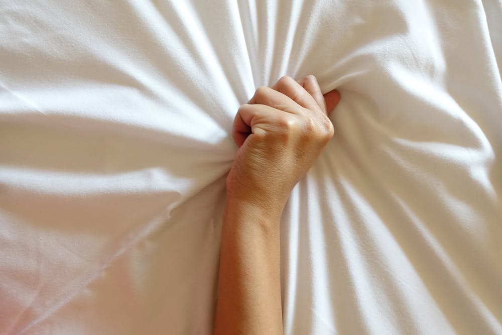 Hand grabbing bed sheet