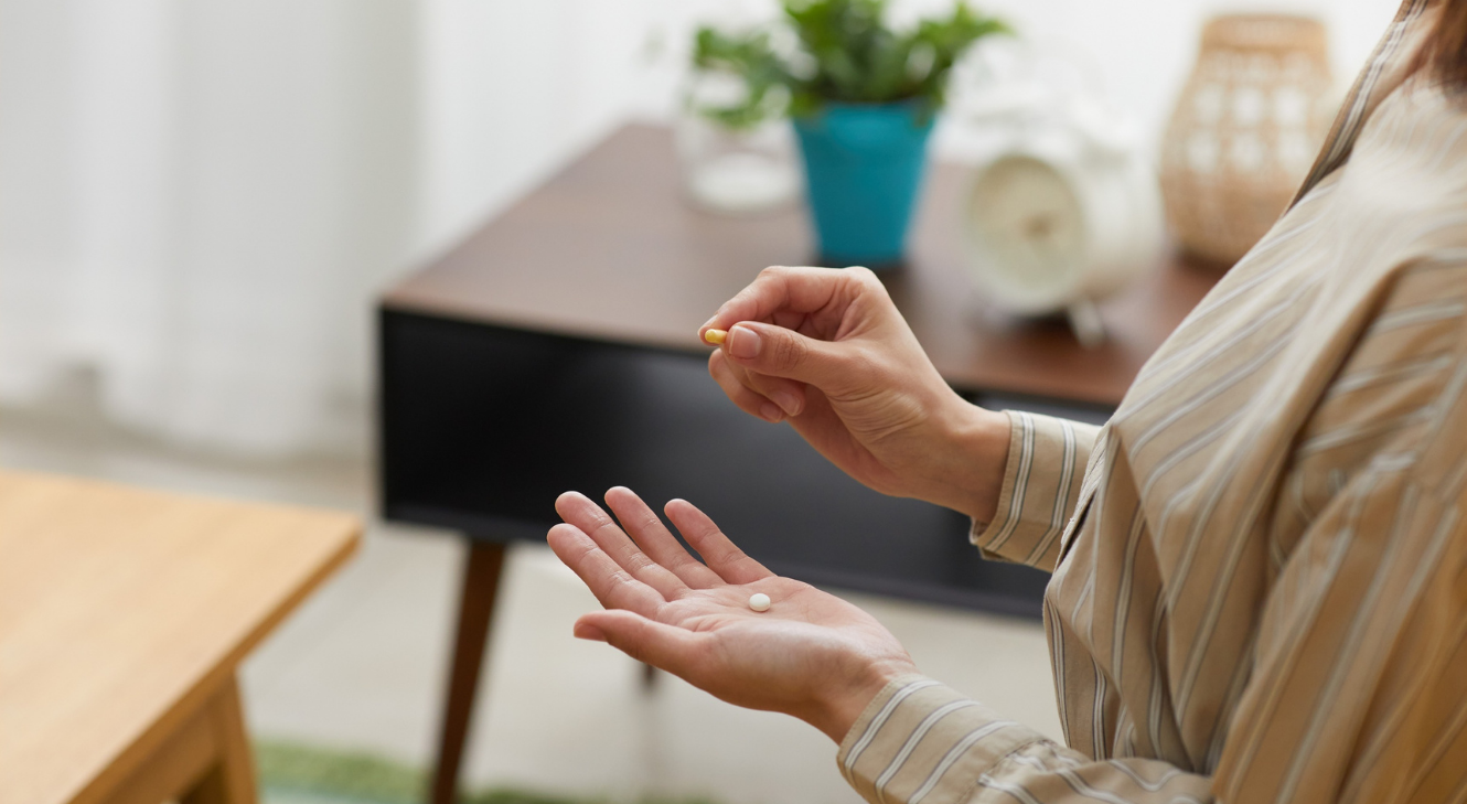 A woman holding supplement pills in her hand.