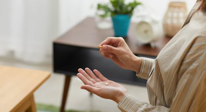 A woman holding supplement pills in her hand.