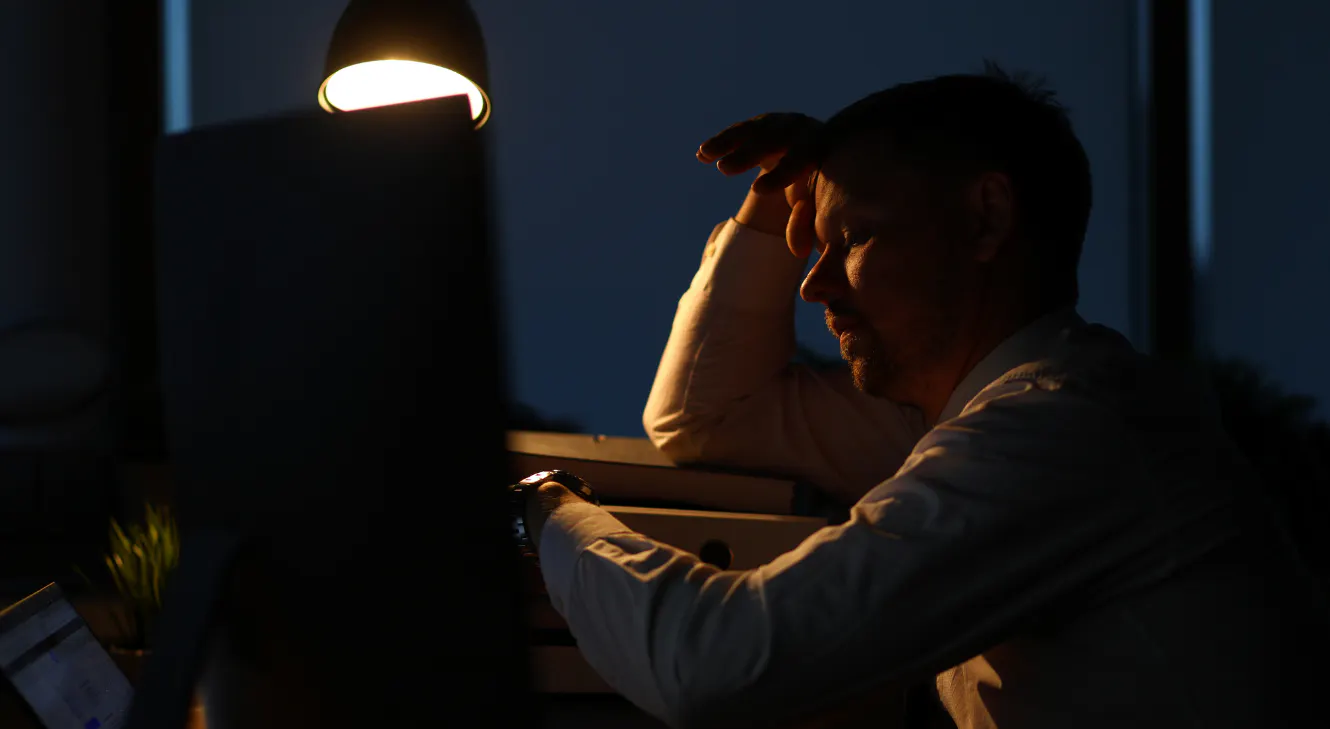 A man looking tired in the dark.
