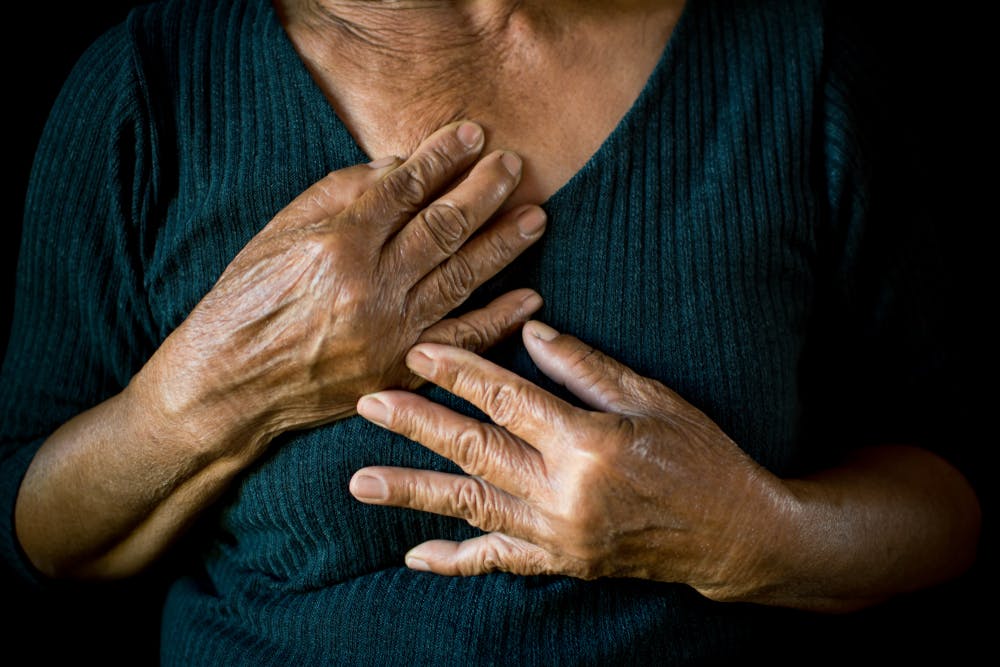 Person with chest pain placing hands on chest
