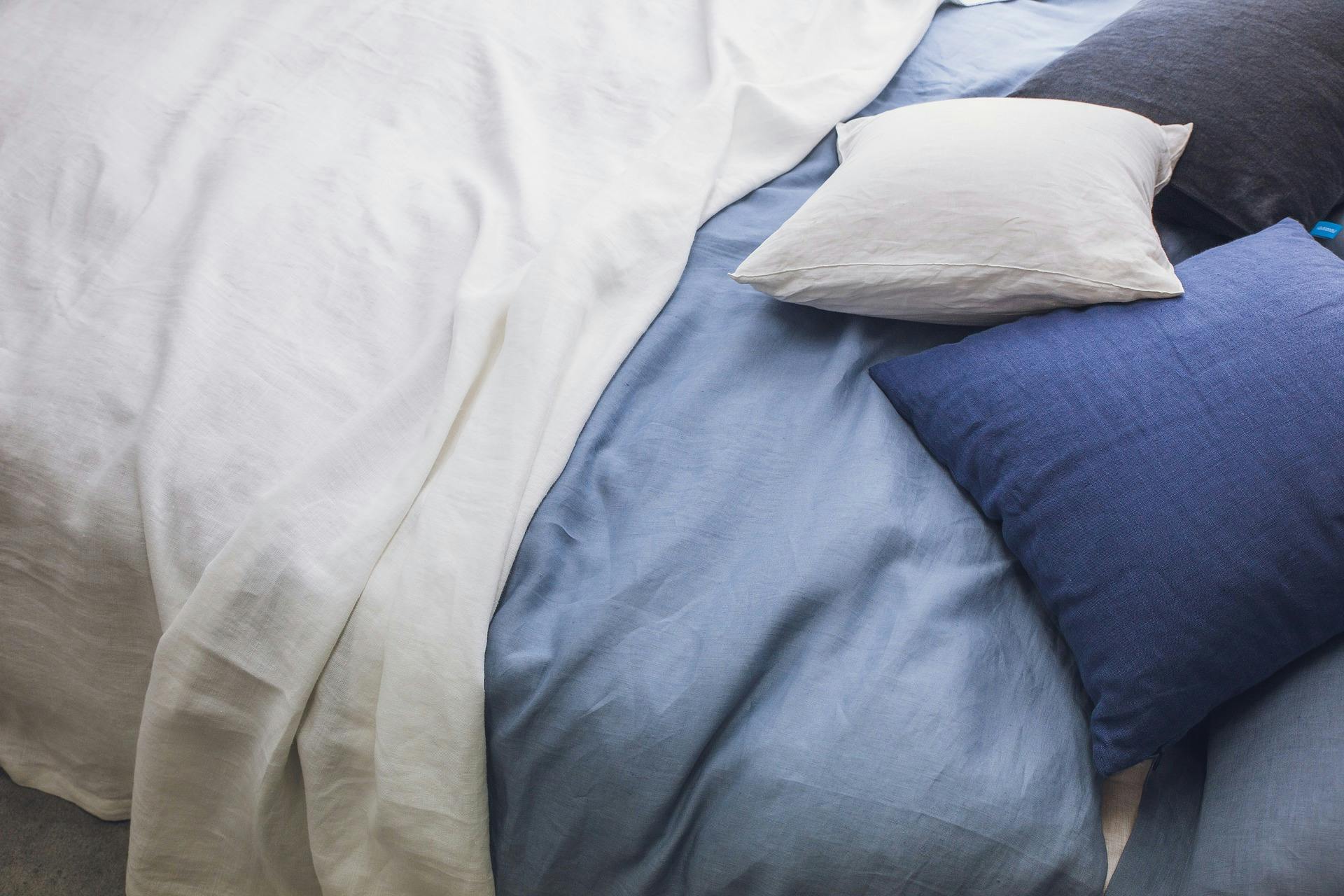 Unmade bed, blue and white pillows