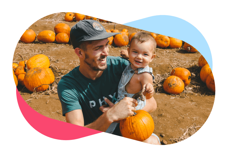 Smiling father holding son in pumpkin field
