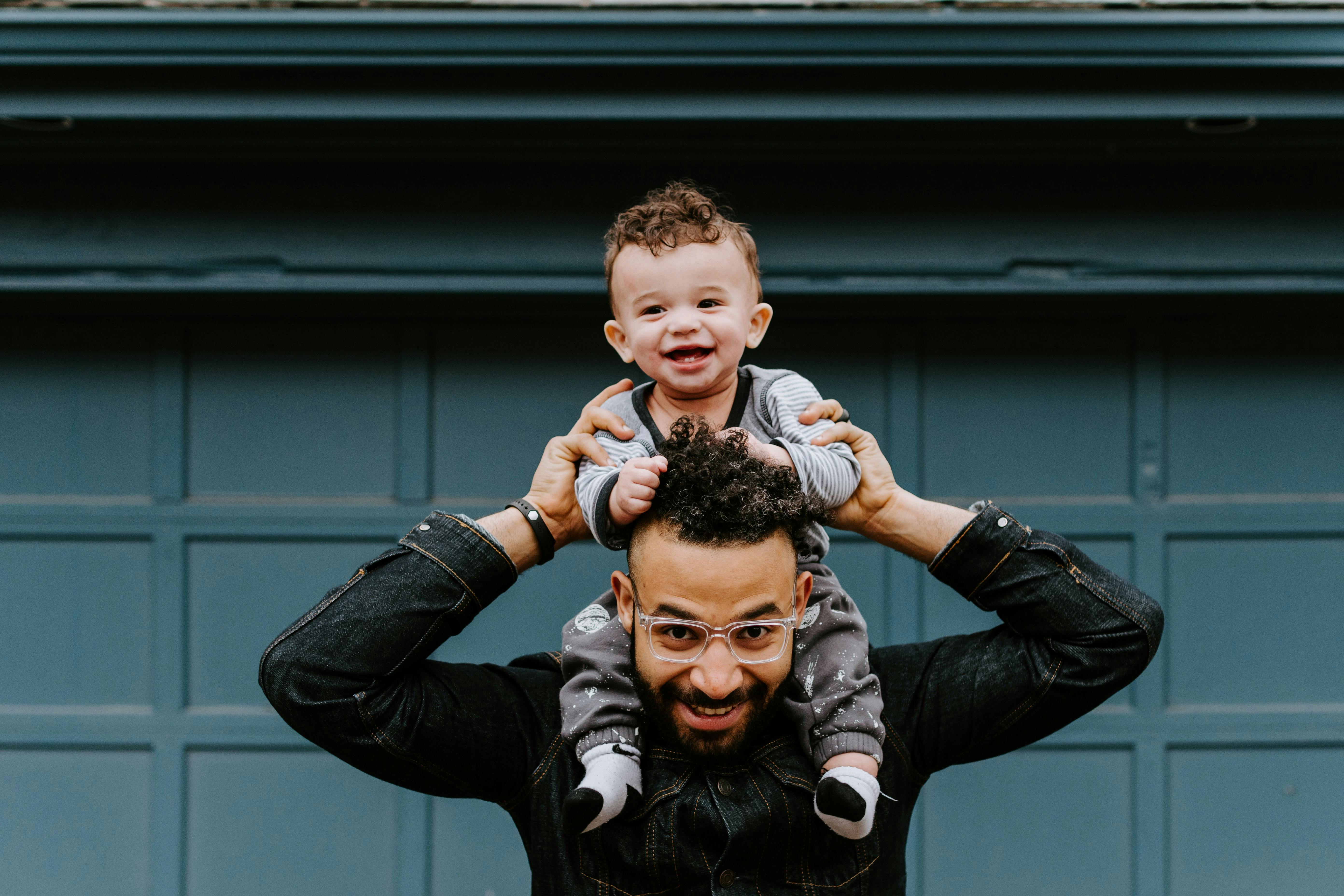 Smiling young dad carrying son on shoulders