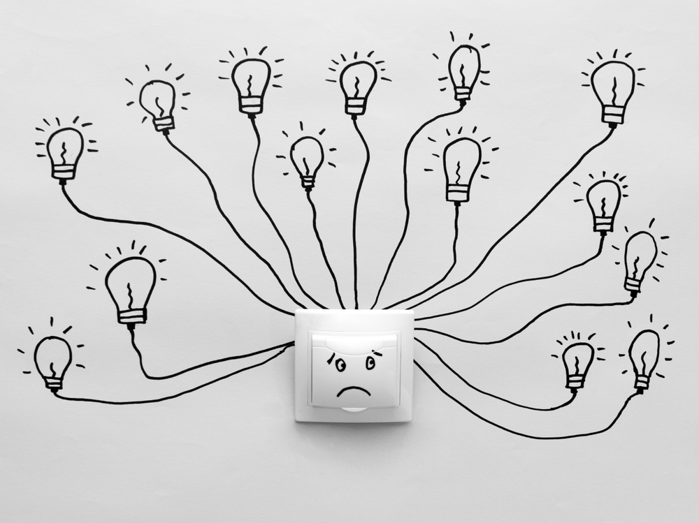 Chronic fatigue syndrome concept — black and white light switch with sad face surrounded by light bulbs