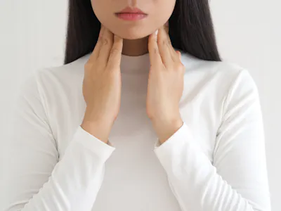 Woman touching thyroid gland on front of neck