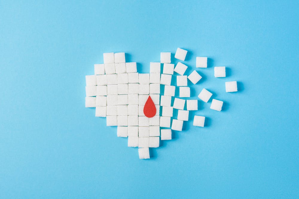 Diabetes — heart and blood sugar cubes on blue background