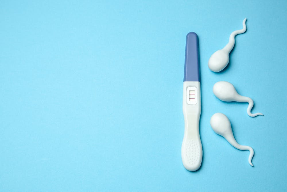Pregnancy test and male sperm on blue background