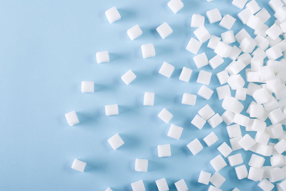White sugar cubes scattered on blue background