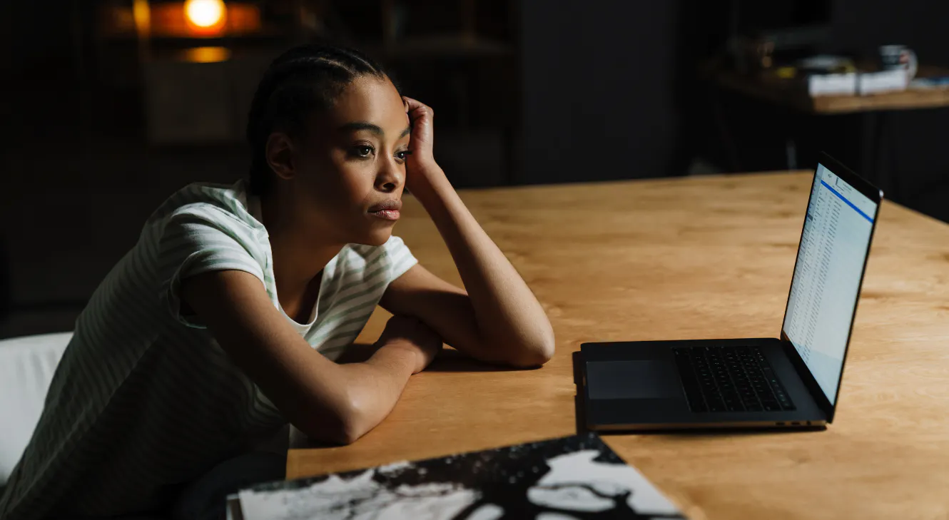 A tired woman sitting in front of a laptop.