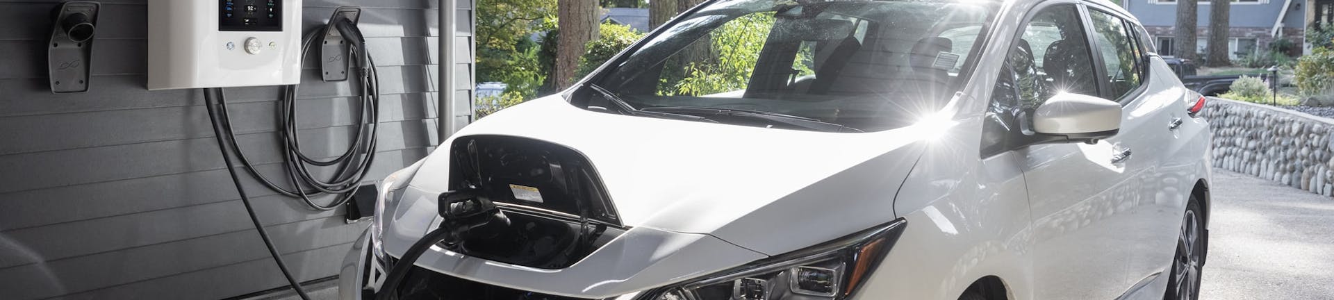 A Nissan Leaf being charged by a dcbel r16 smart home energy station in a garage.