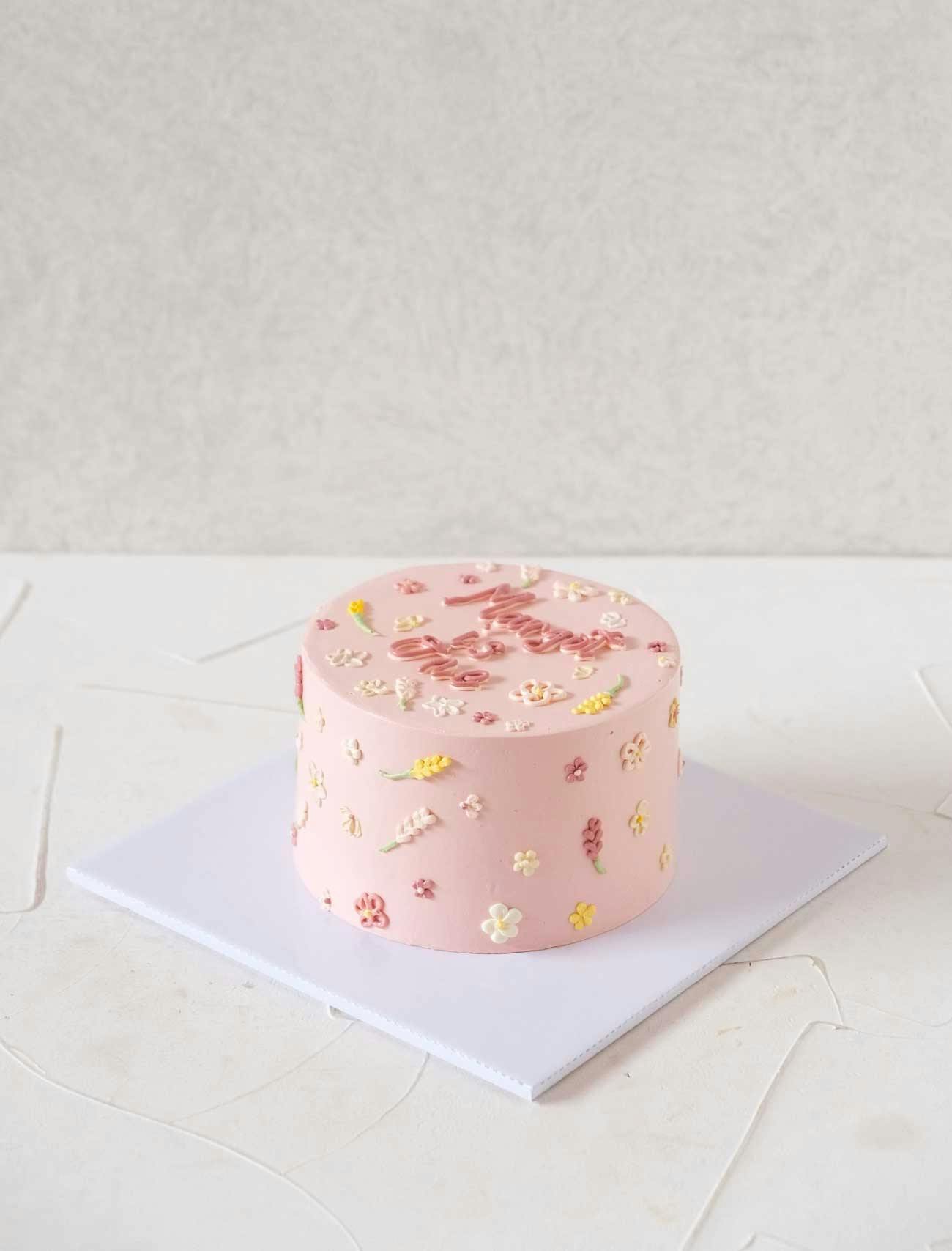 Pink and round celebration cake design that says "Margot is One"