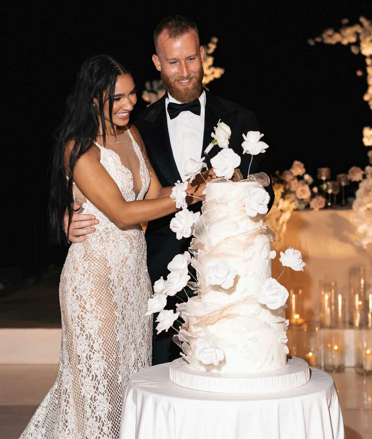 Bride cutting her wedding cake with her husband smiling and watching