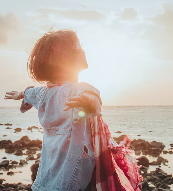 Votre bien-être représenté par une personne libre et heureuse sur une plage.