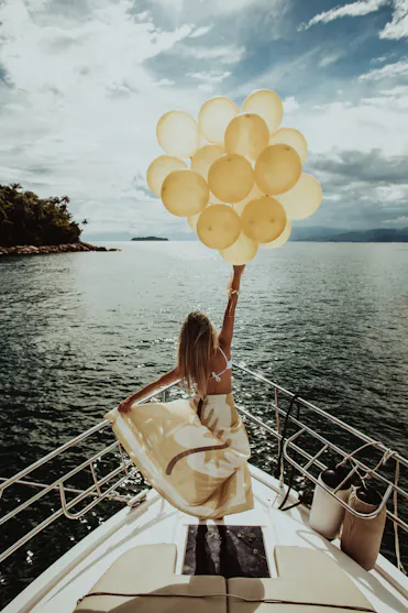 Femme sur un bateau tenant un bouquet de ballons