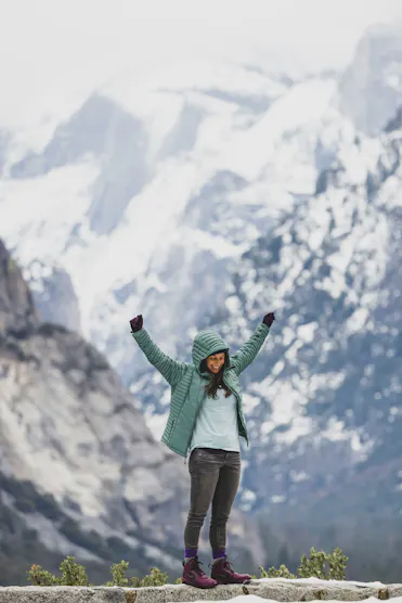 femme avec doudoune bleu devant montagne enneigée