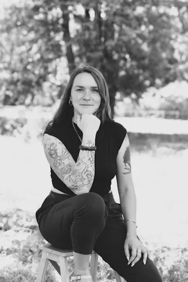 camille laroque femme sur un tabouret en nature avec visage qui repose sur une main 