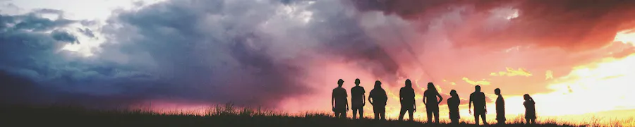 groupe de personnes devant un soleil couchant