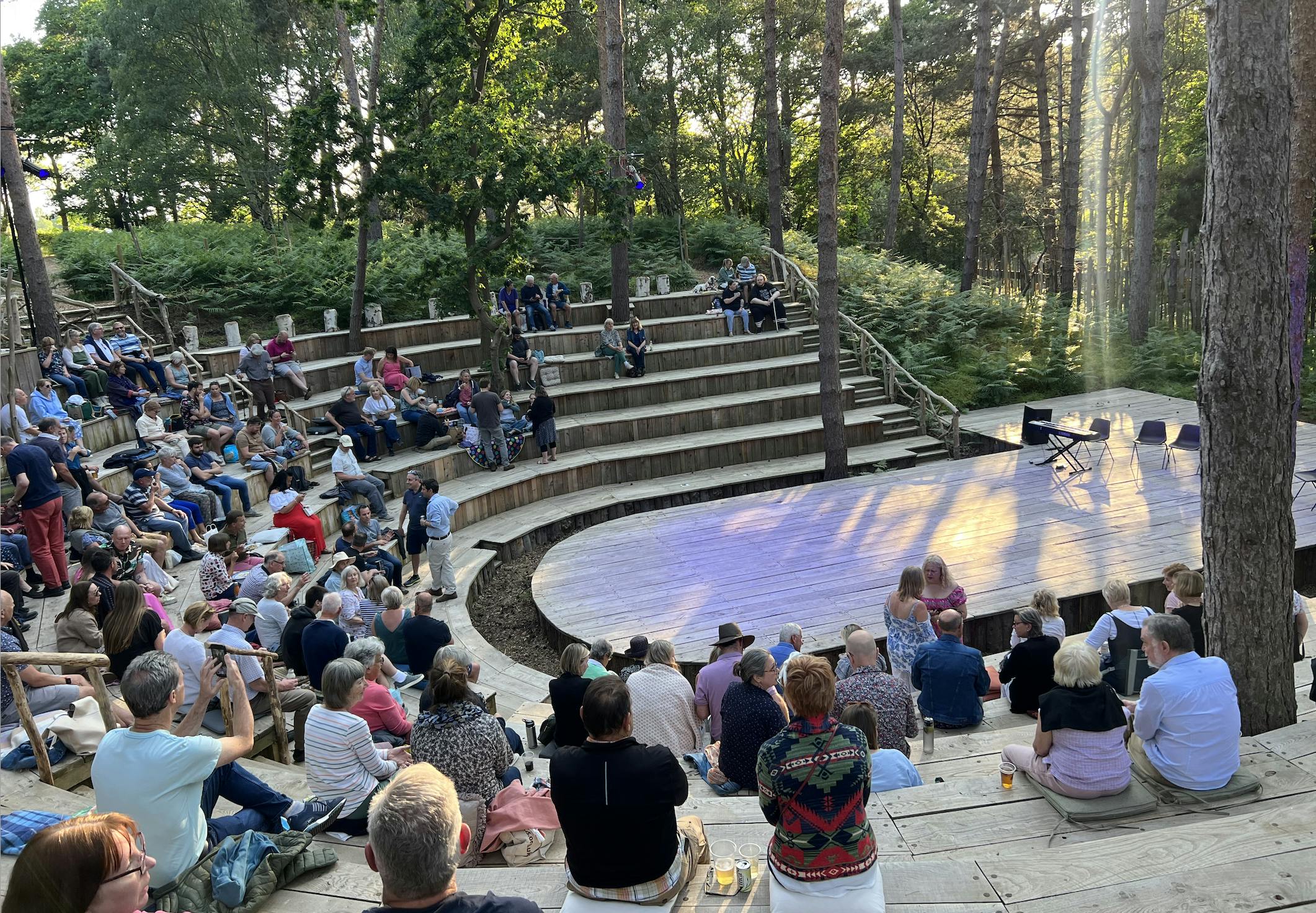 Thorington Theatre photo of the sun-drenched stage surrounded by trees from the audience perspective