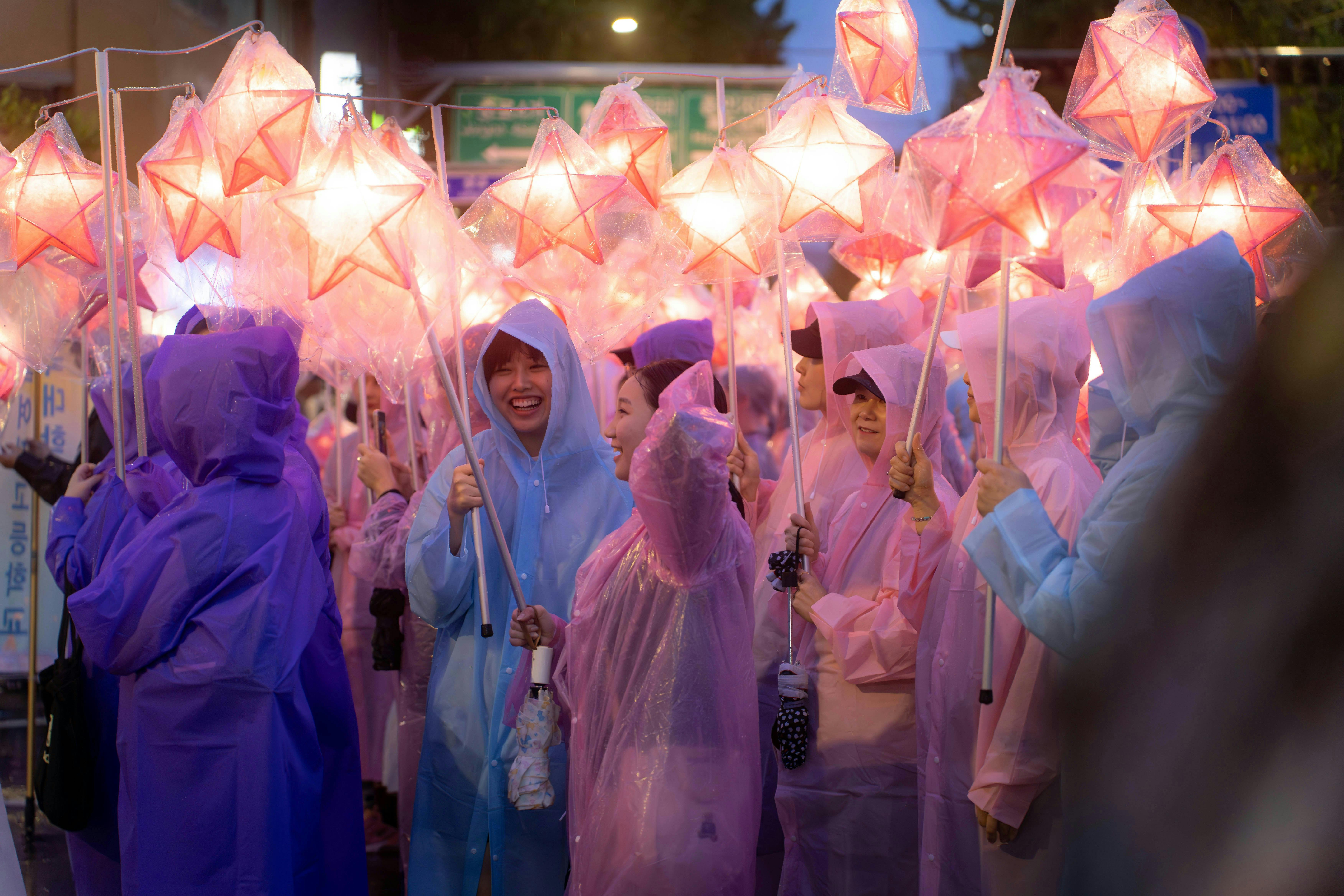 People wearing purple and pink ponchos holding star lanterns