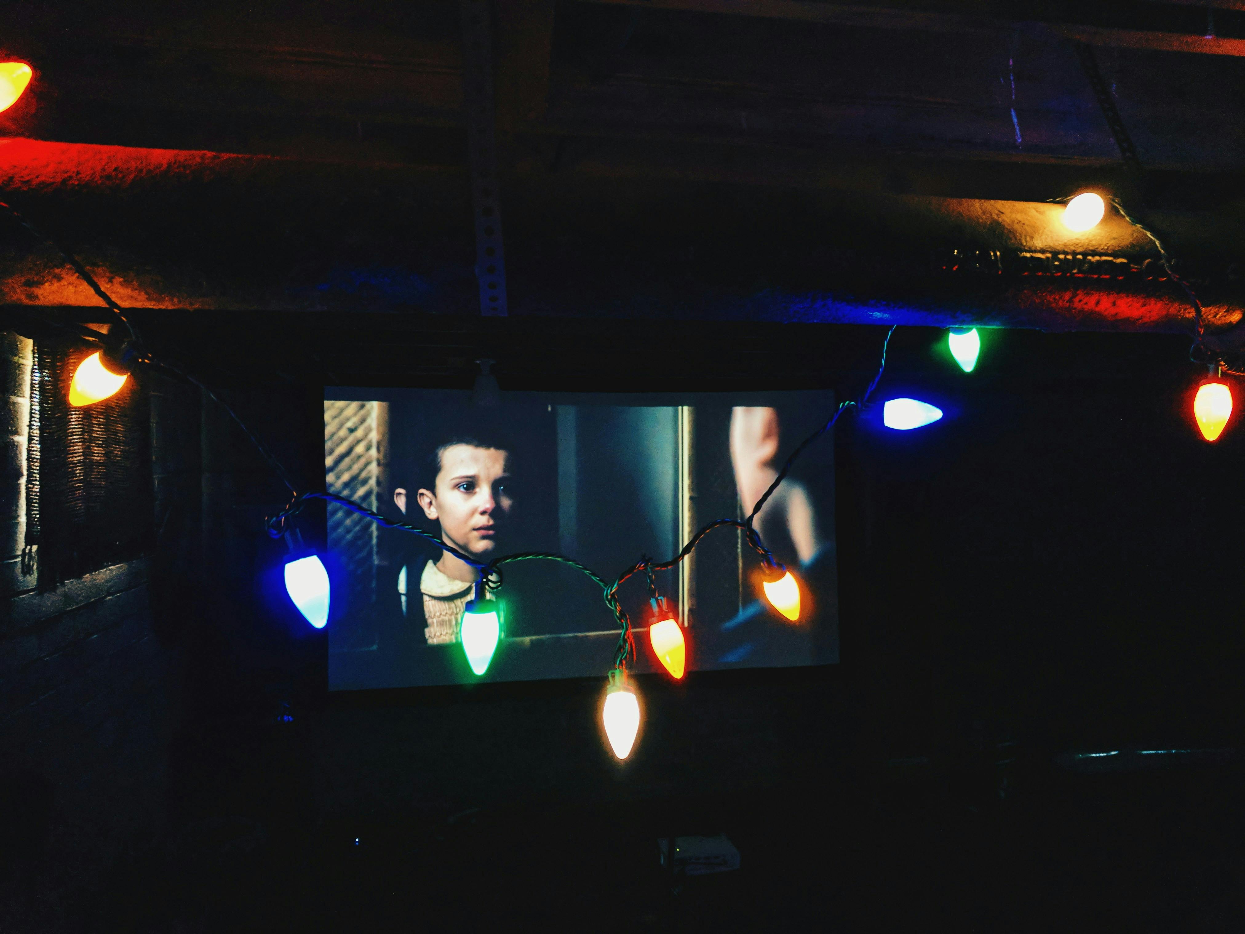 Screen showing Eleven on Stranger Things with multicolored fairy bulb lights