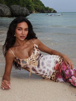 Model wearing a leopard and floral print maxi dress laying on the beach