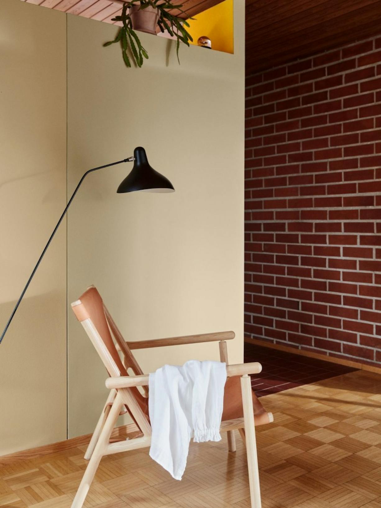 Wooden Chair and Black Lamp in a Yellow Room with Red Brick Wall 